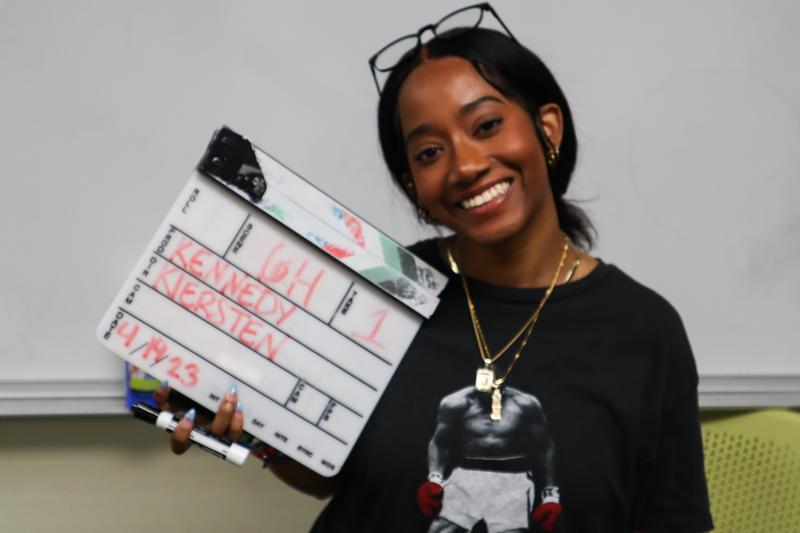 Jayla smiling and holding a film clapperboard